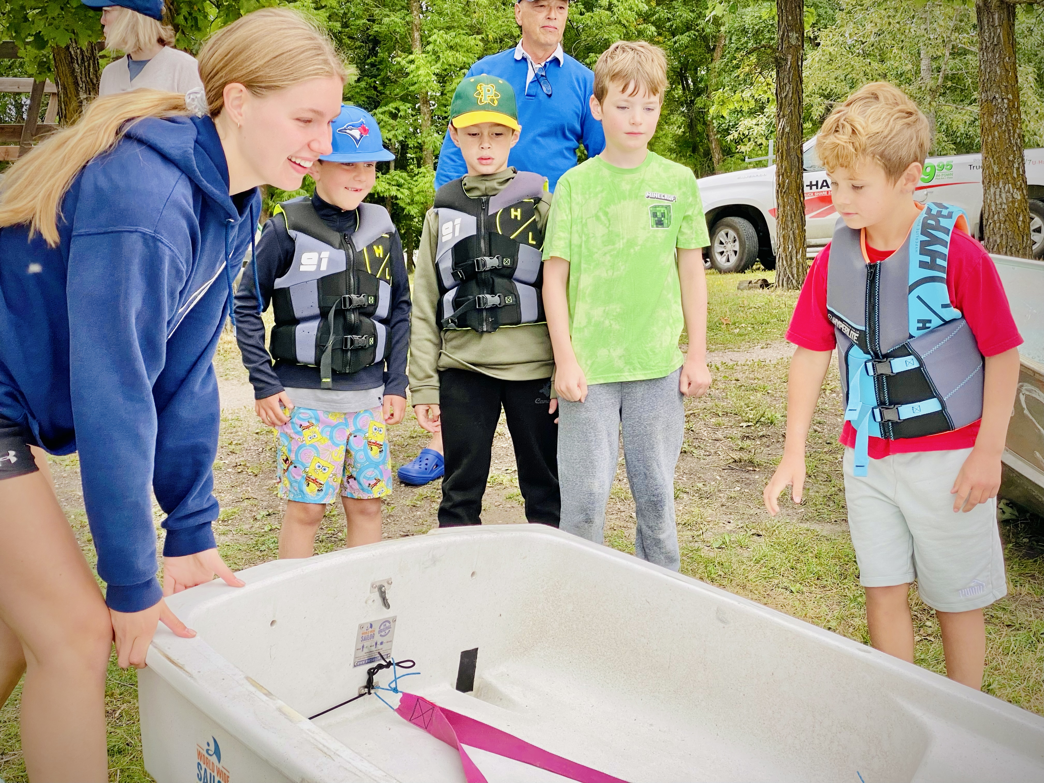 Sailing coach demonstrating a boat to children